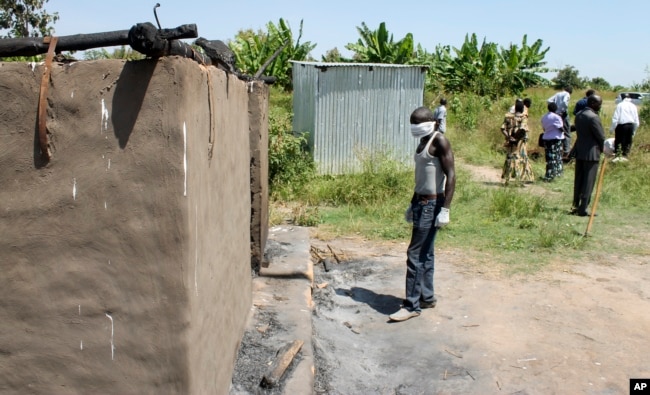 FILE - A man collecting bodies to bury in a mass grave approaches a burned hut containing charred corpses, on the outskirts of Yei, a center of the country's renewed civil war, southern South Sudan, Nov. 15, 2016.