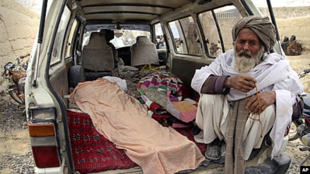 An elderly Afghan man sits in a minivan next to the covered body of a person allegedly shot dead by a U.S. service member in Panjwai, Kandahar province, Afghanistan, Sunday, March 11, 2012.