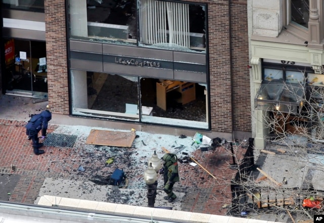 FILE - One of the blast sites on Boylston Street near the finish line of the 2013 Boston Marathon is investigated by two people in protective suits in the wake of two blasts, April 15, 2013.
