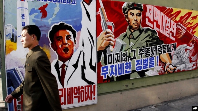 A North Korean man walks past propaganda posters in Pyongyang, North Korea, that threatens punishment to the "U.S. imperialists and their allies," March 26, 2013.