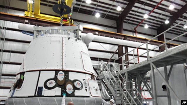 The SpaceX Dragon capsule is lifted to be placed atop its cargo ring inside a processing hangar at Cape Canaveral Air Force Station in Florida. 
