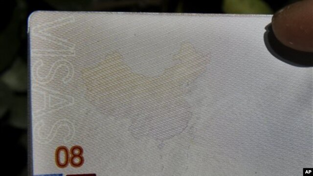 A Chinese man holds up a Chinese passport with details on a page that shows dashes which include the South China Sea as part of the Chinese territory outside a passport office in Beijing, China, Friday, Nov. 23, 2012. (AP Photo/Ng Han Guan)