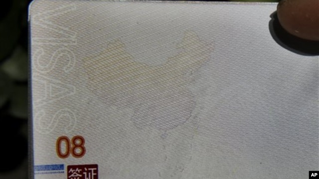 A Chinese man holds up a Chinese passport with details on a page that shows dashes which include the South China Sea as part of the Chinese territory outside a passport office in Beijing, Nov. 23, 2012. 