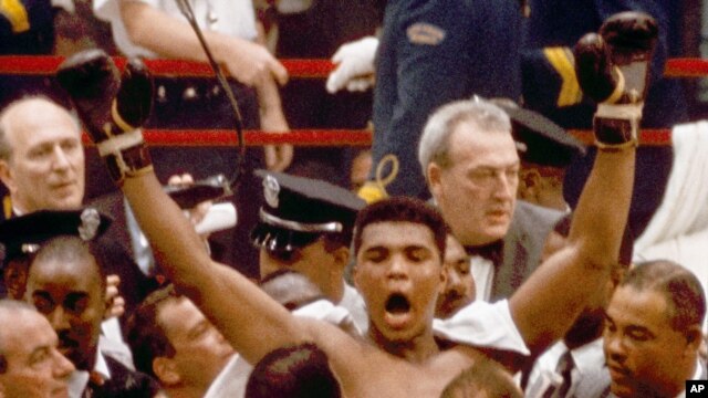 Muhammad Ali, or Cassius Clay at the time, strikes a familiar pose as he shouts "I am the greatest," as he leaves the ring, arms raised, following his defeat of former heavyweight boxing champion Sonny Liston in Miami Beach, Fla., February 25, 1964.