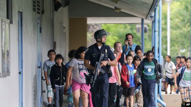 Một cảnh sát viên dẫn đường cho các trẻ em đang trong một cuộc dã ngoại bên ngoài Ðại học Santa Monica, bang California, ngày 7/6/2013.