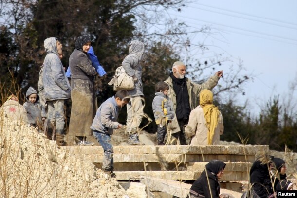 Internally displaced people covered in mud wait at the town of Khirbet Al-Joz to get permission to cross into Turkey, near the Syrian-Turkish border in Syria, Feb. 7, 2016.