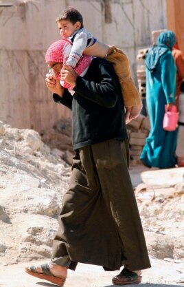 A Syrian refugee carries a child on his shoulders in Sidon, southern Lebanon Mar. 6, 2013.