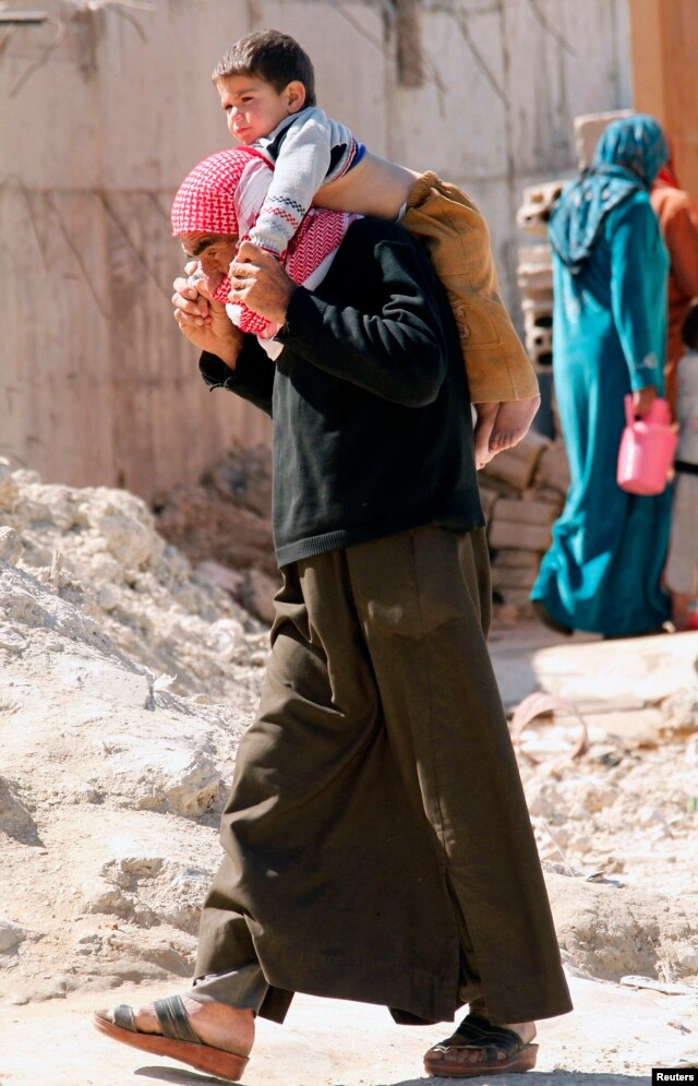 A Syrian refugee carries a child on his shoulders in Sidon, southern Lebanon Mar. 6, 2013.