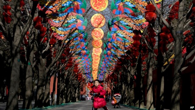 2016年2月2日孩子滑板车的女孩在北京张灯结彩准备迎接中国农历新年的庙会所在地地坛公园玩耍。