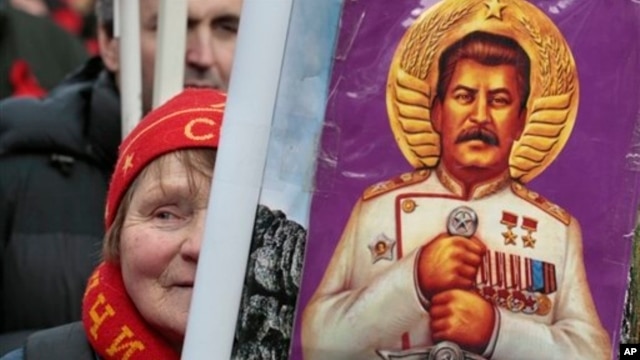 A woman holds a portrait of Soviet dictator Josef Stalin during a communist rally marking Defenders of the Fatherland Day, Moscow, Feb. 23, 2013.