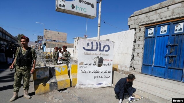 Um miliciano Houthi fica de guarda como um perito forense inspeciona a cena de uma explosão perto do palácio republicano em Sana, 07 de fevereiro de 2015.