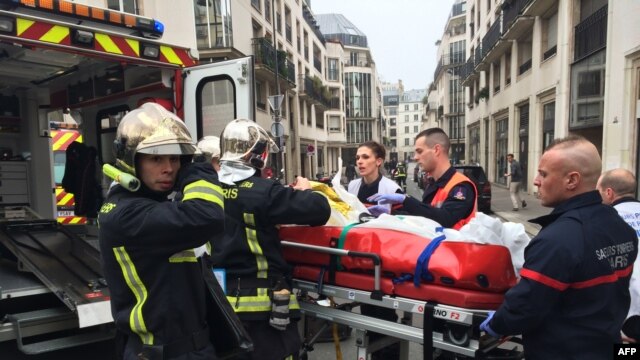 Nhân viên cứu hỏa khiêng người bị thương ra khỏi hiện trường vụ nổ súng tại trụ sở tuần báo trào phúng Charlie Hebdo ở Paris, ngày 7/1/2015.