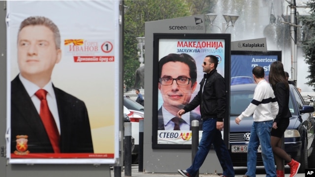 Young people pass beside boards with election posters of Gjorge Ivanov, left, current Macedonian President and a candidate of the ruling conservative VMRO-DPMNE party.