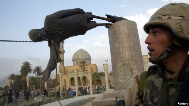 A U.S. soldier watches as a statue of Iraq's President Saddam Hussein falls in central Baghdad in this photo dated April 9, 2003.