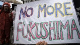 A demonstrator holds a "No more Fukushima" sign during a rally, protesting against restarting the Ohi nuclear power plant's reactors in front of the prime minister's official residence in Tokyo, Saturday, June 16, 2012.