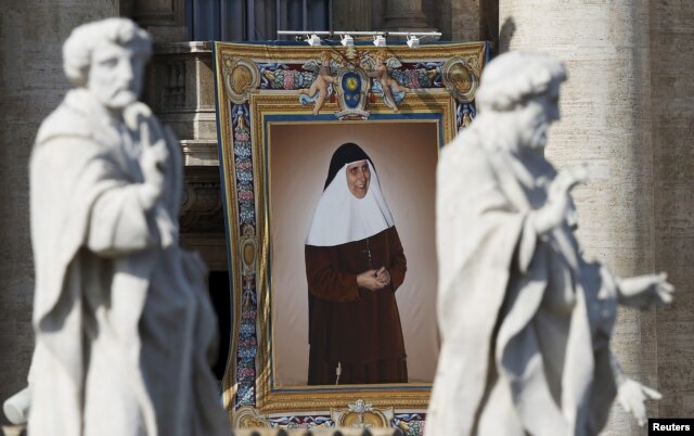 A tapestry showing Maria Isabel Salvat Romero hangs from a balcony as Pope Francis leads the mass for a canonization in Saint Peter's Square at the Vatican, Oct. 18, 2015.