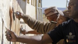 Members from the South African correctional service repair a wall at a school where former South African President Nelson Mandela went as a child as they celebrate his birthday in Qunu, South Africa, Wednesday, July 18, 2012.