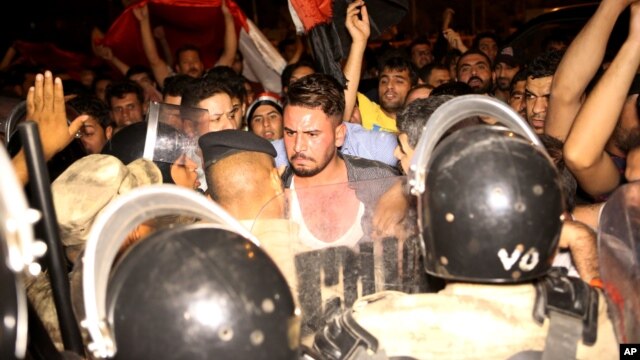 Iraqi riot police prevent protesters from storming the provincial council building during a demonstration in Basra, 340 miles (550 kilometers) southeast of Baghdad, Iraq, early Saturday, May 21, 2016. 