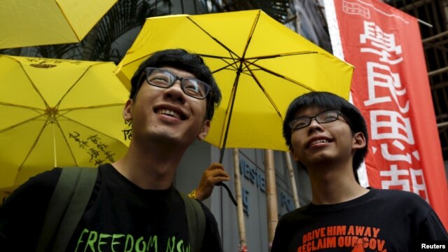 Joshua Wong (phải) và Nathan Law cầm dù vàng, biểu tượng phong trào Chiếm Trung, đứng trước trụ sở cảnh sát Hồng Kông, hôm 14/7/2015.