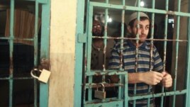 A Palestinian inmate stands behind the bars of a Hamas-run jail in Gaza City after prayers during the holy month of Ramadan, July 23, 2012.
