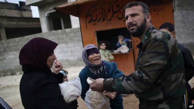 A woman asks a Free Syrian Army fighter to sell her bread, in Maaret Misreen, near Idlib, Syria, December 13, 2012.