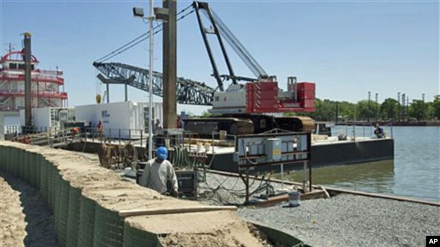 A worker from ABL Fabricators, L.L.C. walks along a temporary levee system set up along the Bayou Boeuf waterway in Amelia, Louisiana, May 17, 2011