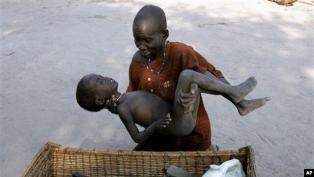 In this Dec. 21, 2005 file photo, a mother gently places her son in a basket as she takes him to a Medecins Sans Frontieres clinic after he contracted malaria, in Lankien, Southern Sudan. (AP Photo/Karel Prinsloo, File)