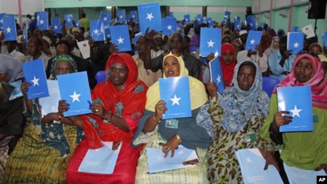 Somalia's constituency assembly members hold up copies of the proposed new constitution during the beginning of a nine-day meeting in Mogadishu, July 25, 2012.