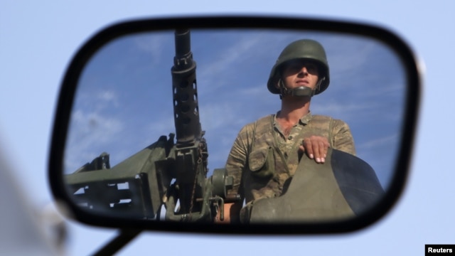 A Turkish soldier is reflected on a mirror as he stands guard on top of an armored personnel carrier on the Turkish-Syrian border near the Akcakale border crossing, October 4, 2012. 