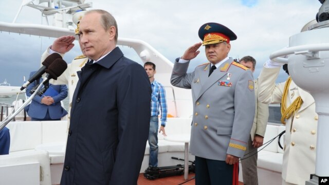 O presidente russo, Vladimir Putin Comentários de um desfile Marinha em Baltisk, oeste da Rússia, 26 de julho de 2015, durante as celebrações do Dia da Marinha russa. O ministro da Defesa, Sergei Shoigu fica à direita.