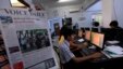 Journalist holds up a sample copy of The Voice Daily newspaper at a news room in Rangoon, March 31, 2013.