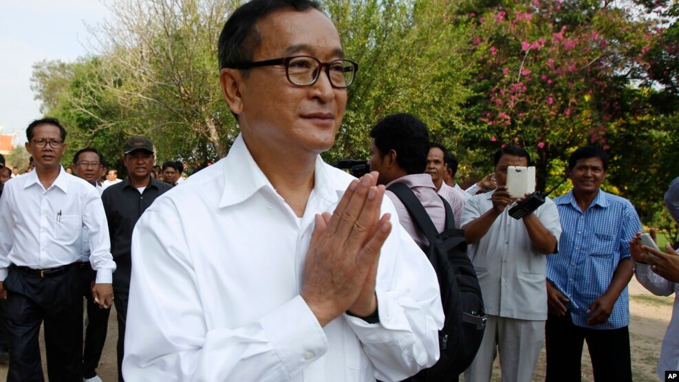 Cambodian main opposition Cambodia National Rescue Party leader Sam Rainsy, front, greets his supporters as his arrives at Choeung Ek memorial on the outskirts of Phnom Penh, Cambodia, Friday, May 17, 2015. 