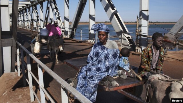 People on donkey-drawn carts cross a strategic bridge over a dam on the Niger River secured by French forces in Markala, Mali, January 18, 2013.