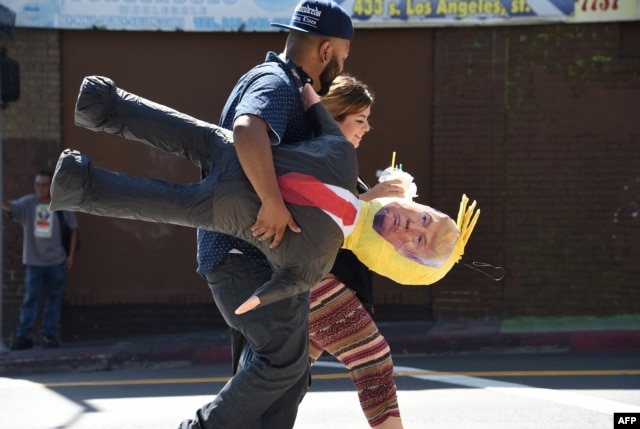 FILE - A Latino couple walk with a pinata of Republican presidential candidate Donald Trump in downtown Los Angeles, Sept. 23, 2015. "The Hispanic community in general feels abandoned by the Republican party,” one Prince William County resident says.