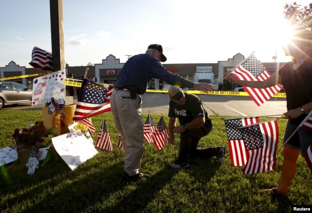 Mourners places flags at a growing memorial in front of the Armed Forces Career Center in Chattanooga, Tennessee, July 16, 2015.