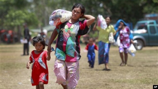 Thai women and children walk to a waiting bus to transport them home after sporadic fighting between Thai and Cambodian troops was reported at a refugee camp in Surin province, northeastern Thailand, May 2, 2011