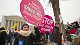 Abortion rights protesters hold signs as anti-abortion activists march past the Capitol to the Supreme Court in Washington, Jan. 25, 2013.