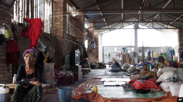 An elderly Kachin refugee and children, inside a shelter, look after the belongings of others who were out working near the China-Burma border in Yunnan province, China, August 11, 2012.