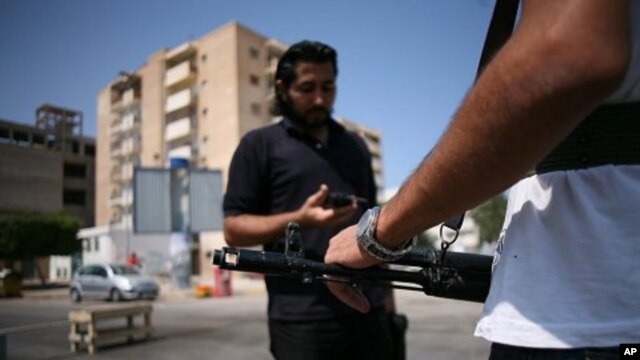 Men stand guard at an anti-Gadhafi checkpoint in downtown Tripoli, August 27, 2011