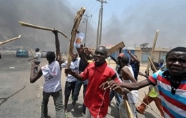 People holding wooden and metal sticks demonstrate in Nigeria's northern city of Kano where running battles broke out between protesters and soldiers on Monday.
