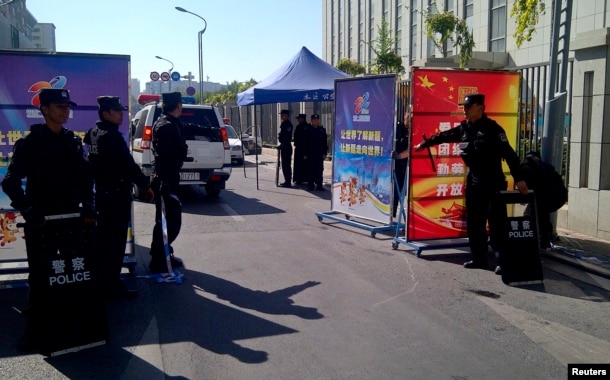 FILE - Police with riot gear guard a checkpoint on a road near a courthouse where ethnic Uighur academic Ilham Tohti's trial is taking place in Urumqi, Xinjiang Uighur Autonomous Region, Sept. 17, 2014.