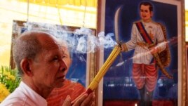 Cambodian man holds the burned incense sticks in front of a painted photo of a Kampuchea Krom Hero, Son Kuy, right, at a ceremony in Phnom, file photo. 