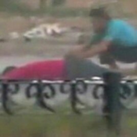 A protester crouches near the body of a man lying on the ground in Hama in this still image taken from video posted on a social media website on August 4, 2011 (Reuters cannot independently verify the content of the video)