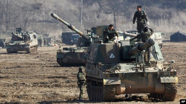 Solados surcoreanos trabajan en sus vehículos de artillería durante los ejercicios militares contra posibles ataques por parte de Corea del Norte.