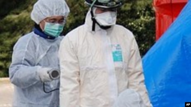 Emergency workers checking each other for radiation exposure in Koriyama, Japan, March 13, 2011