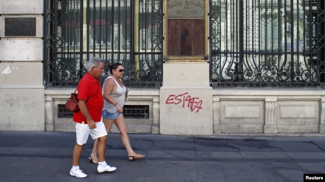 Tourists walk past Spain's former Banco Espanol de Credito in Madrid, August 28, 2012. 