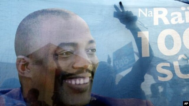Supporters of incumbent President Joseph Kabila are seen celebrating through a banner with his image after provisional election results are announced in Democratic Republic of Congo's capital Kinshasa, December 9, 2011.