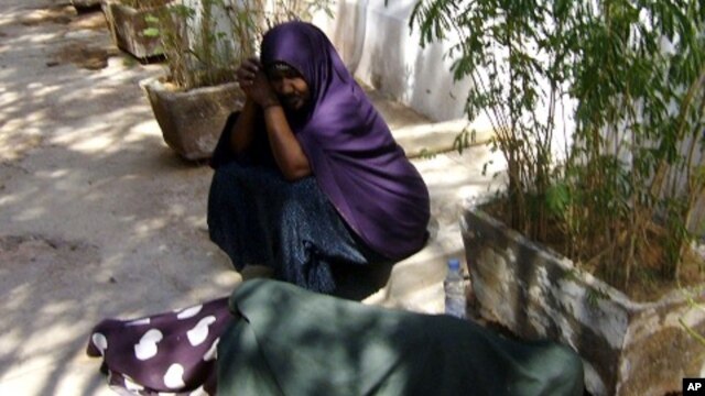 Asha and Muna wait for assistance outside the UNHCR office in Galkayo town. Muna , is sleeping on the floor because she could not withstand the pain in her thigh. She was stabbed by a rapist on Nov. 26 2010.