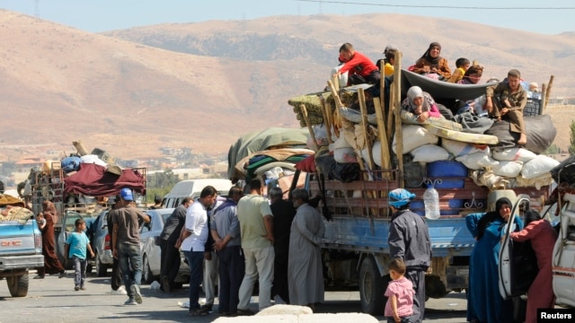 Syrian refugees, fleeing the recent fighting in Arsal, wait by trucks in the Bekaa valley, near the Lebanese border with Syria.