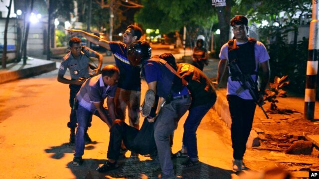 People help an unidentified injured person after a group of gunmen attacked a restaurant popular with foreigners in the Bangladeshi capital Dhaka.